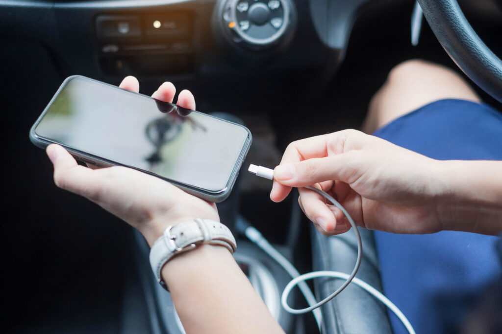 A guy plugs his phone into a charger in a car