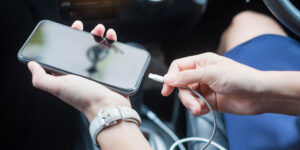 A guy plugs his phone into a charger in a car